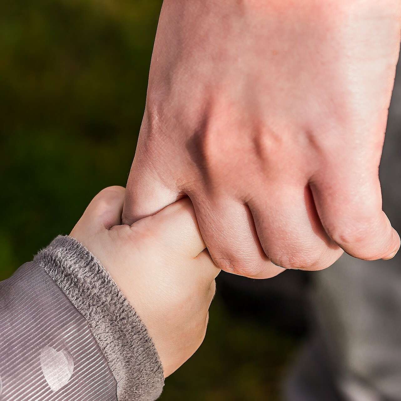 Hand eines Erwachsenen hält Kinderhand
